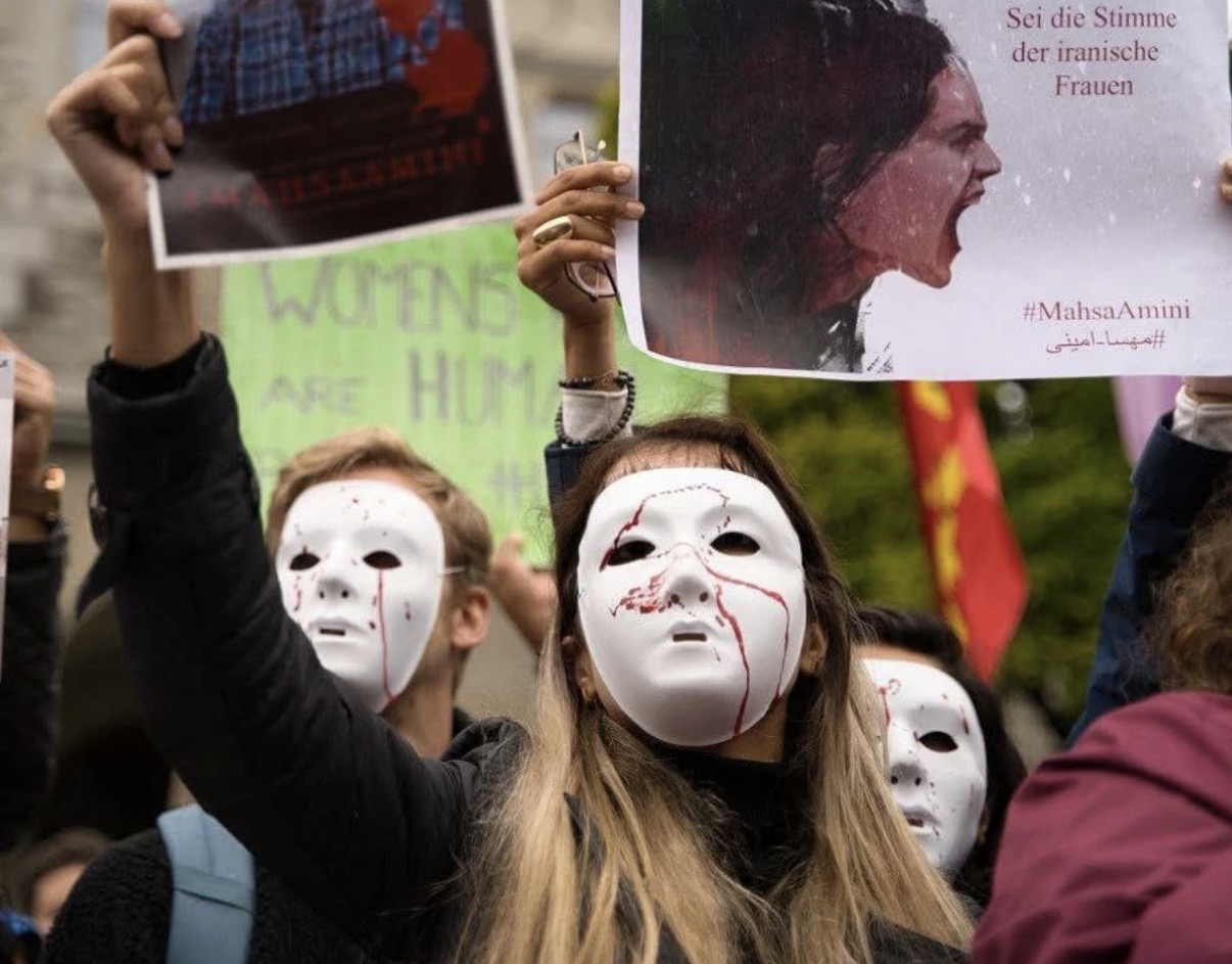 Protesters wearing white masks hold signs for Mahsa Amini at a Woman, Life, Freedom demonstration in Switzerland